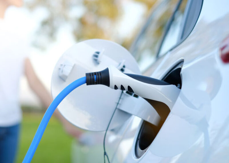 close up of electric car charger connectivity with a white car