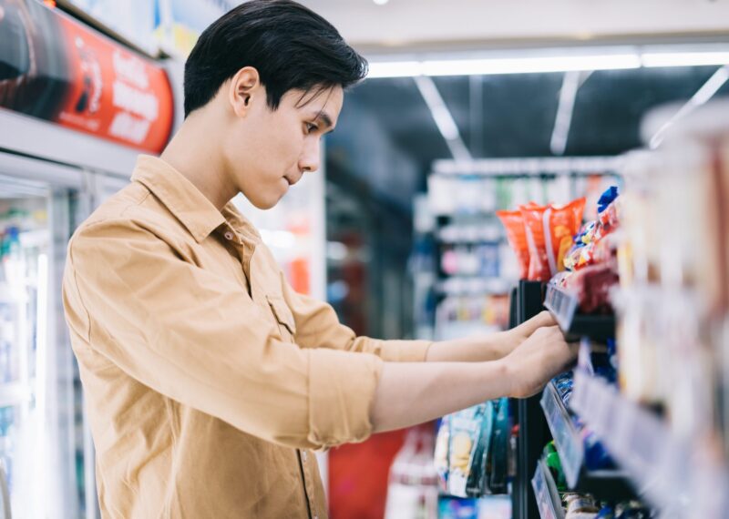 Young asian man browsing convenience store aisle