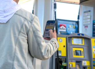 Man using loyalty app on smartphone at fuel pump.