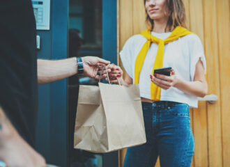 Man handing shopping bag to female customer