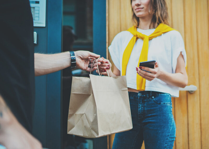 Man handing shopping bag to female customer