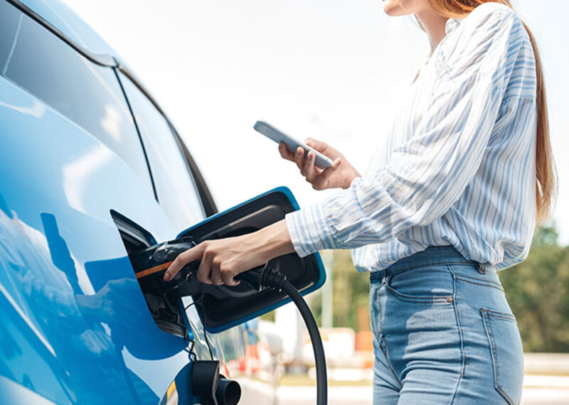 Woman fueling up car while using a phone