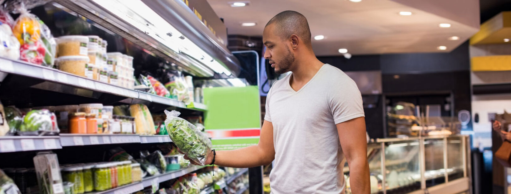 Man at grocery store in gas station holding lettuce