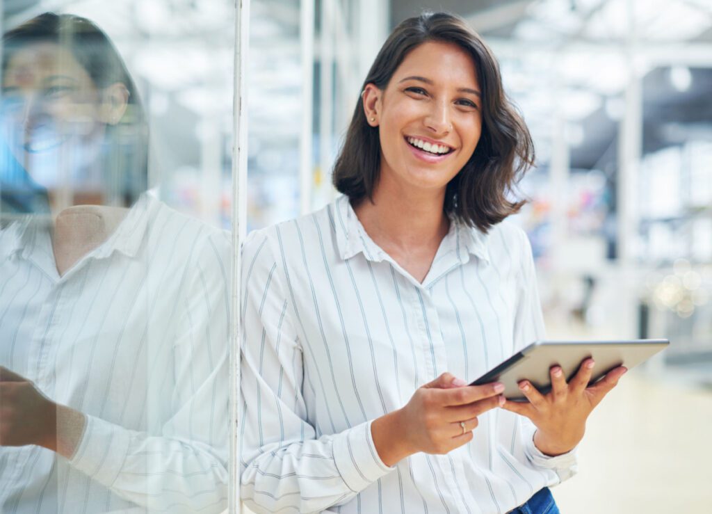 Young adult female smiling while using tablet to simplify convenience retail operations.