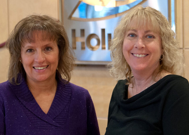 Two women standing in front of Holiday Station Stores sign in lobby