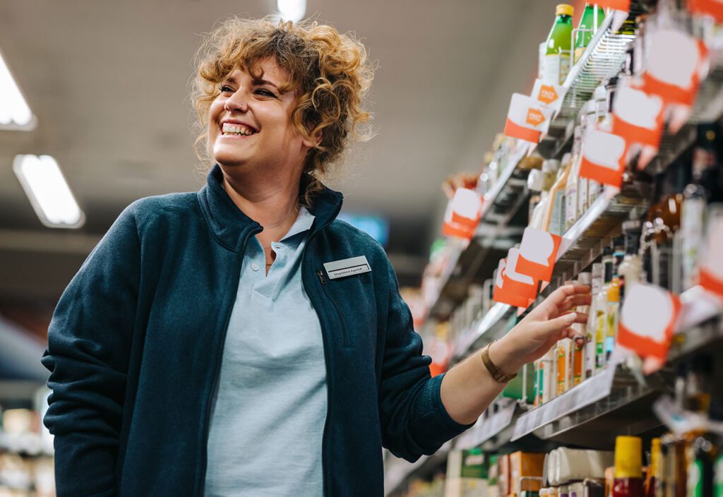 Female CPG employee touching consumer packaged goods products on shelf.
