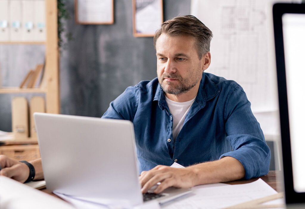 Man sitting at desk using laptop.