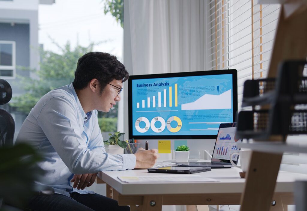 Candid of young asian thai man busy work multiple screen computer or smart tablet on table desk at home in freelance data analyst, data science scientist for business. 