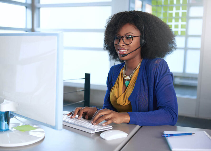 Young woman in blue sweater working at computer