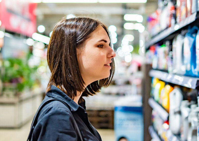 Female shopper looking at cleaning products on shelf in CPG store