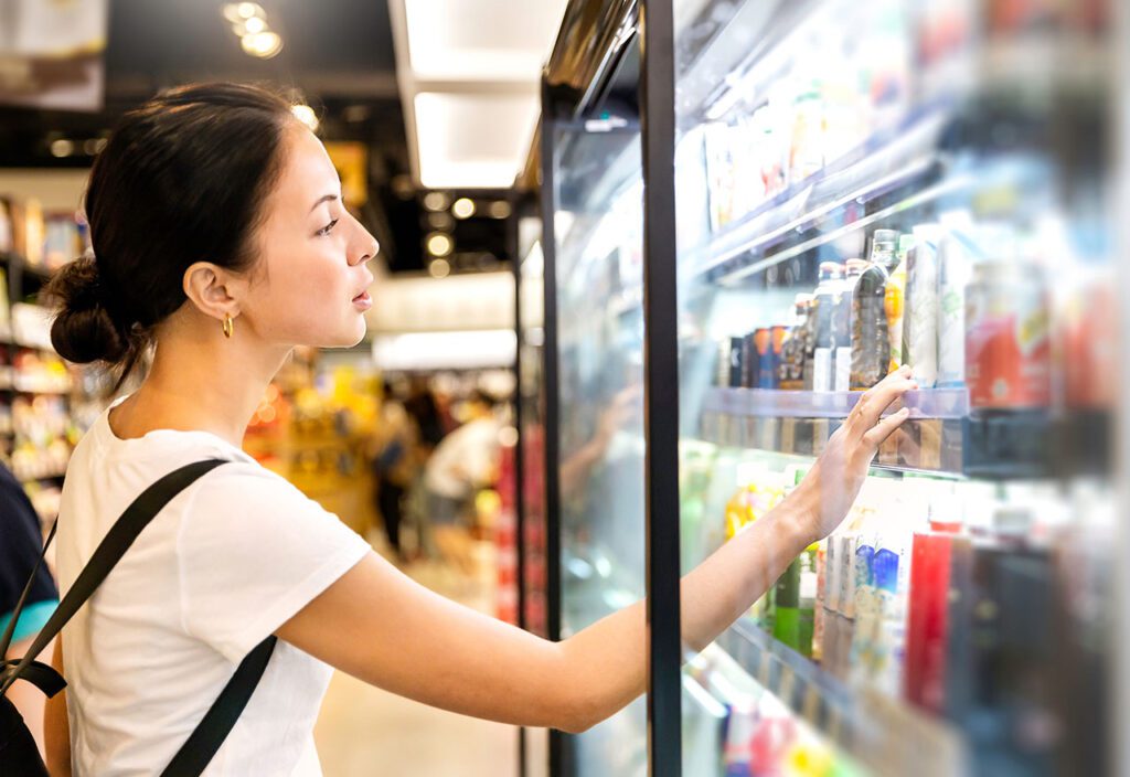 Female shopper shopping for frozen items at consumer pacakged goods store.