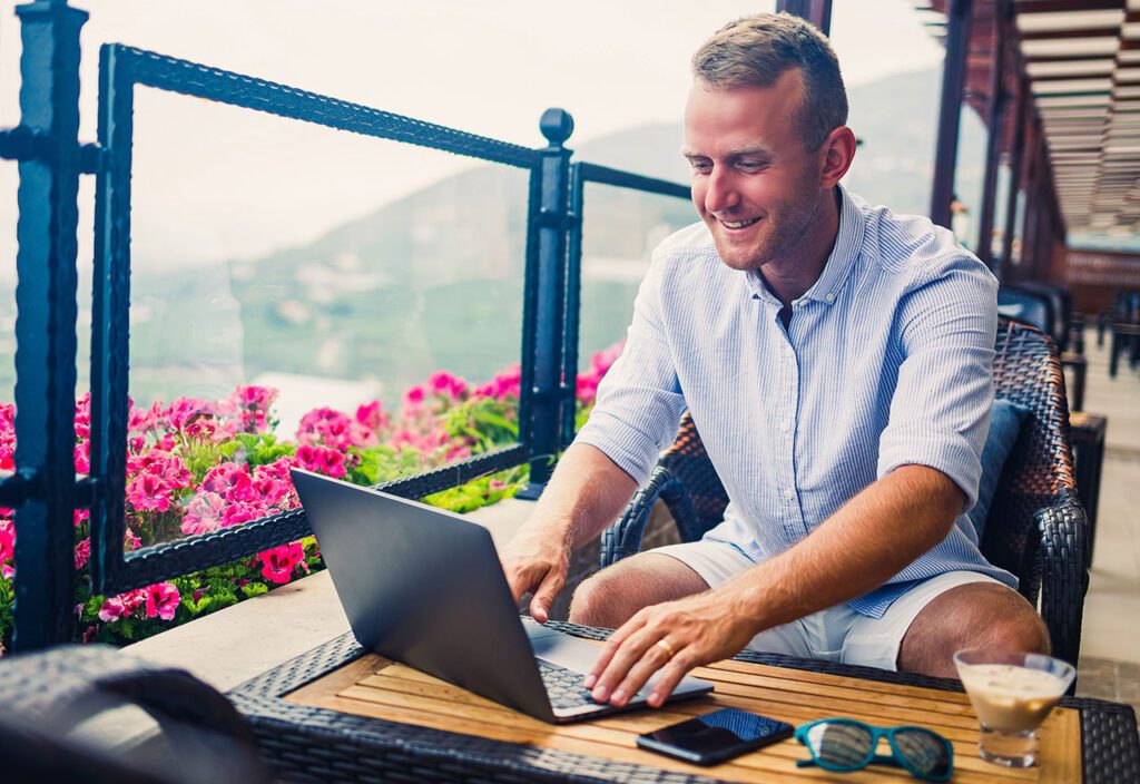 Businessman using laptop for IT work while on vacation.