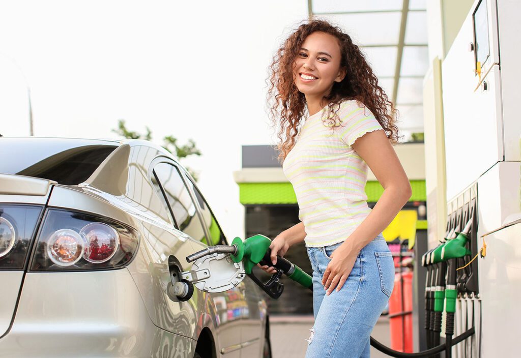 African-American woman filling up car tank at gas station