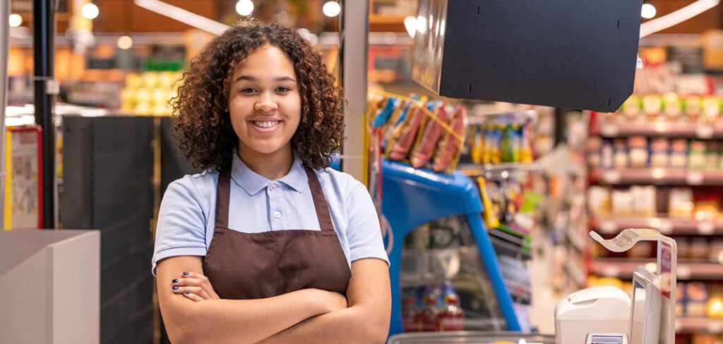 Pretty young smiling African-american female sales clerk looking at you