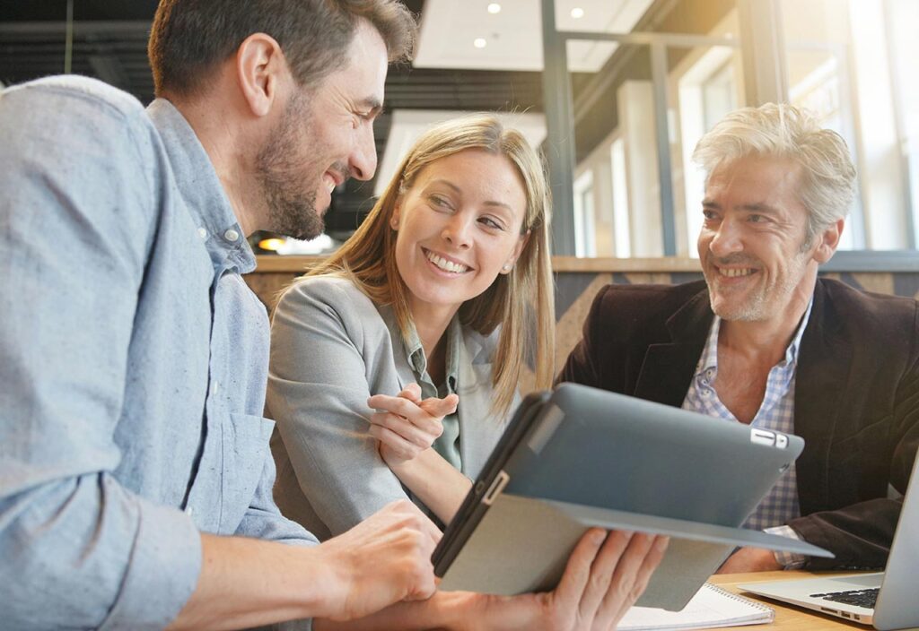 A Team is smiling at each other while working on laptop and tablet  