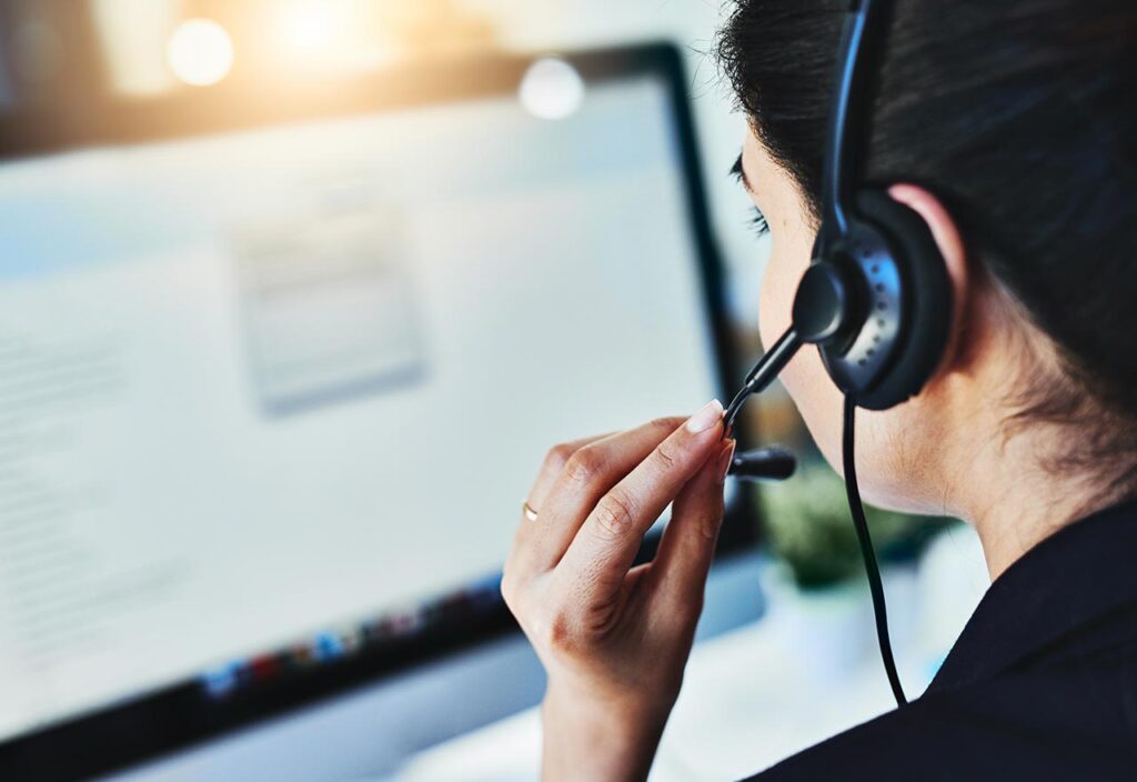 Black-haired woman holding the mic of a headphone while looking at the screen 