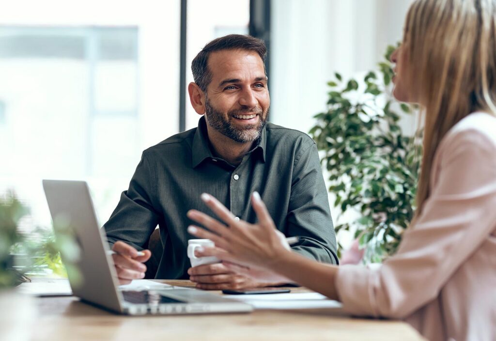 A blond-haired woman explaining something to her fellow co-worker 