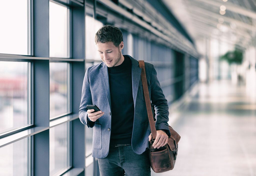 Man using cell phone to access operations data while walking through airport.