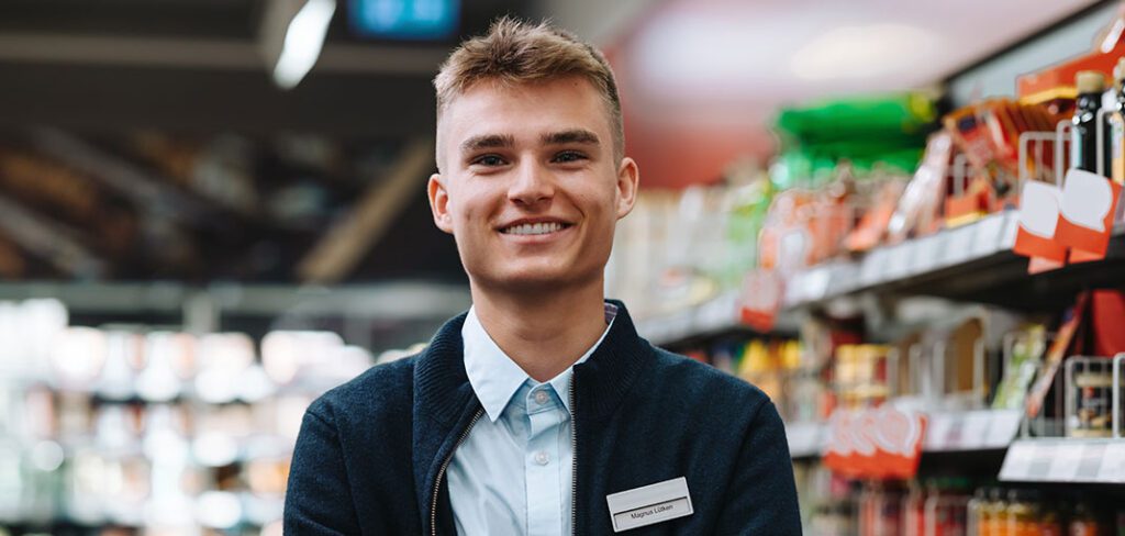 Male employee of CPG retail store smiling with arms folded.
