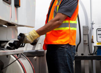 A fuel pump attendant is pumping fuel in a fuel truck
