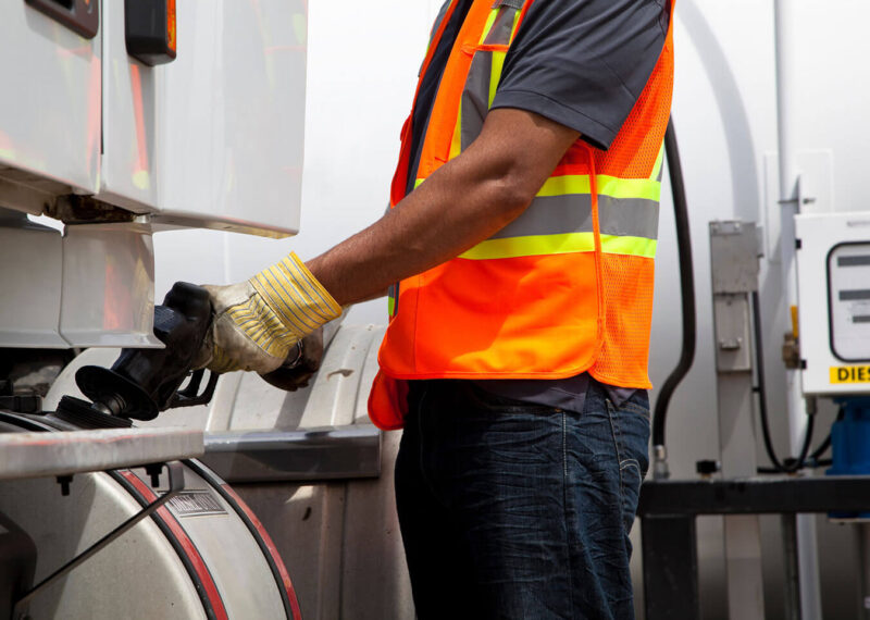 A fuel pump attendant is pumping fuel in a fuel truck