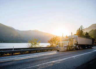 Semi-truck driving down scenic highway with mountain views