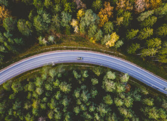 Aerial view of car driving along tree lined road