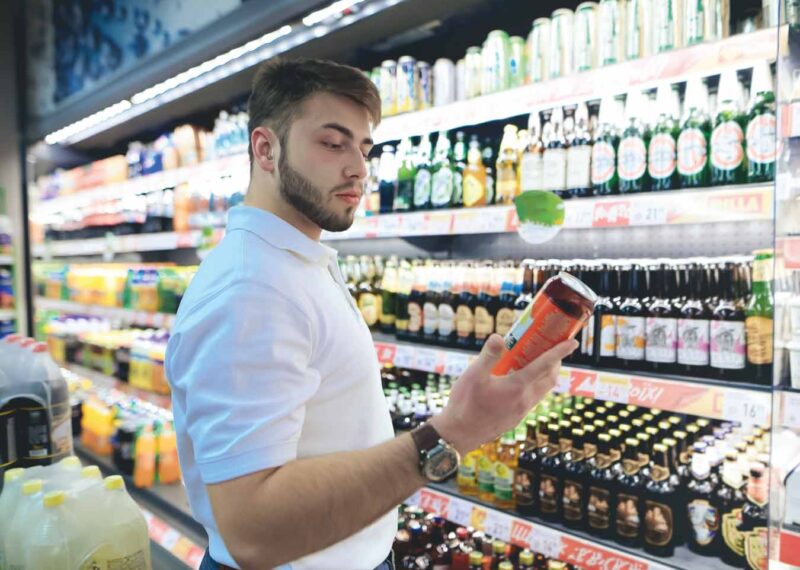 man looking at can in front of beverage aisle