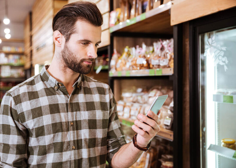 Man looking at mobile phone while shopping in a convenience store