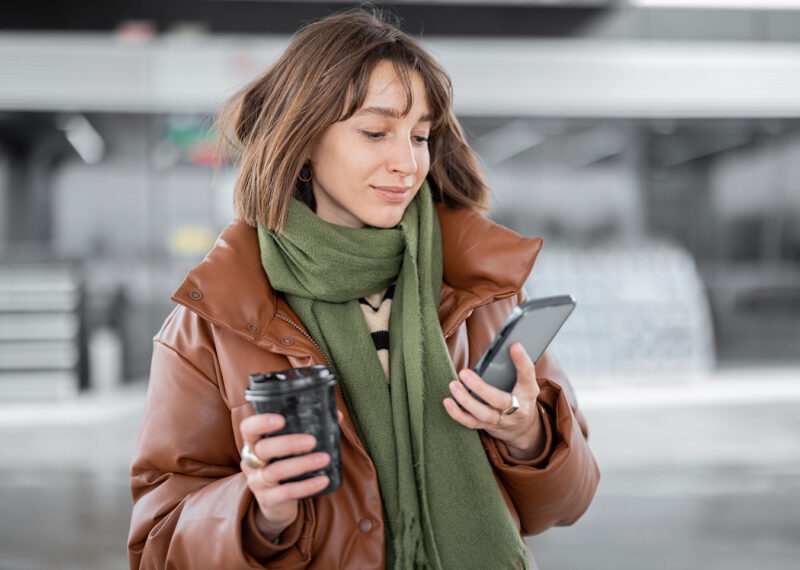Woman holding coffee cup and looking at mobile device