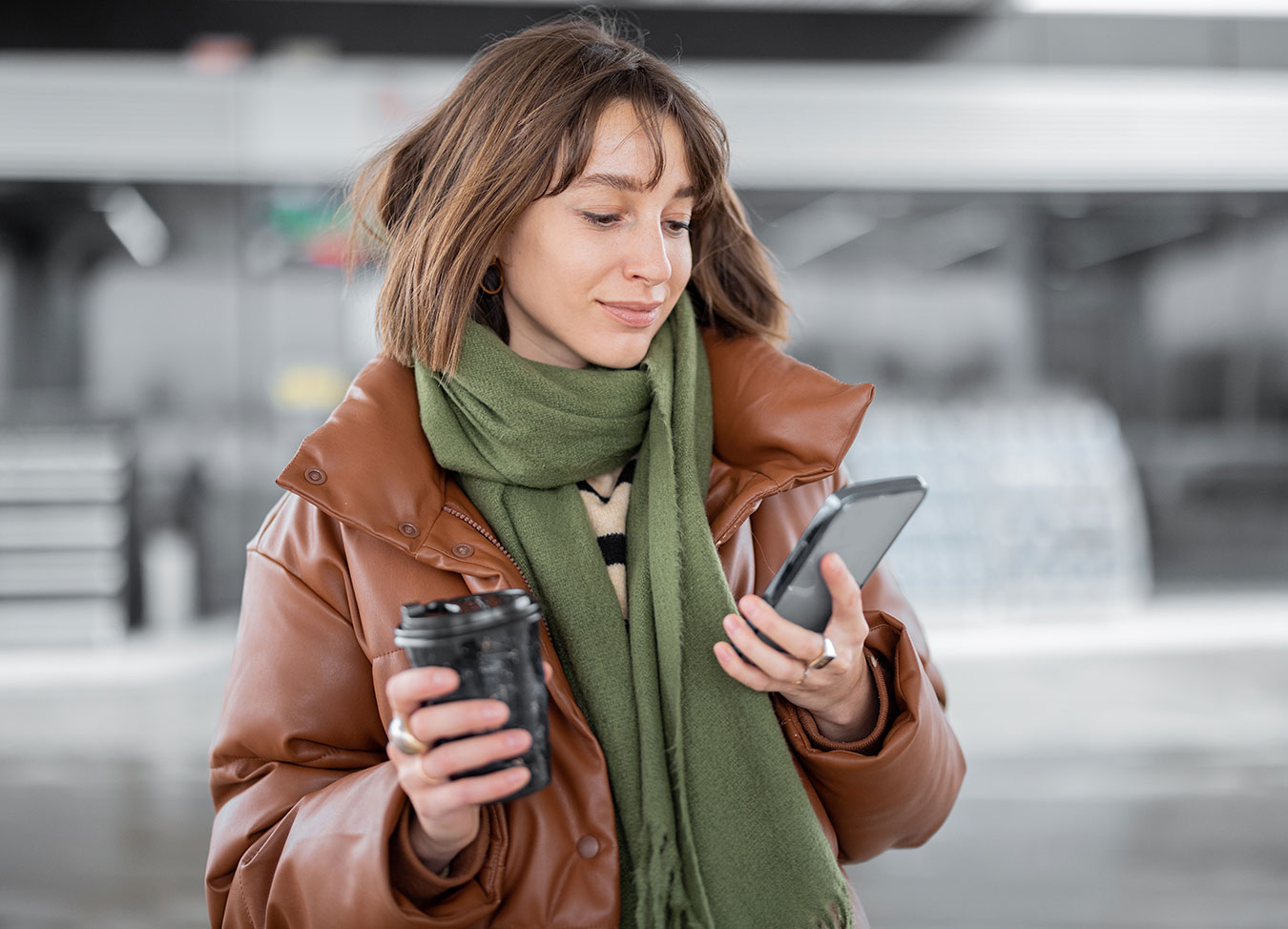 Woman holding coffee cup and looking at mobile device