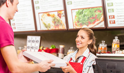 Woman handing a pizza to a man in restuarant