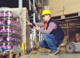 man in hard hat checking warehouse inventory with mobile device