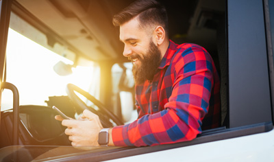 Young handsome bearded man using smart phone in his truck.