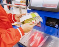 customer scans their own items at the self-service checkout in a convenience store