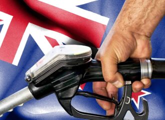 Hand holding gasoline hose against flag of New Zealand