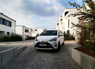 White hybrid Toyota car auto parked in apartment courtyard