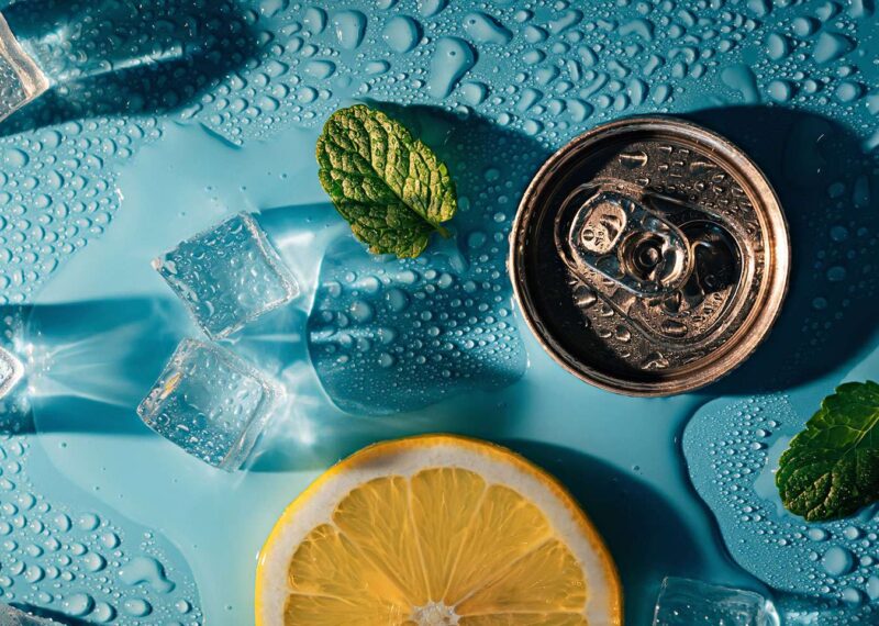 Creative summer composition with lemon slice, mint leaves, beverage can and ice cubes.