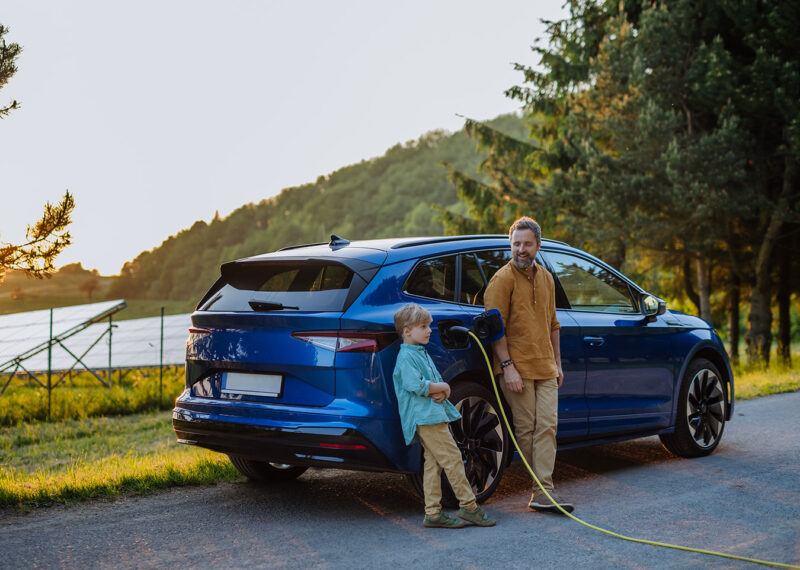 Father and his son charging electric car during their road trip