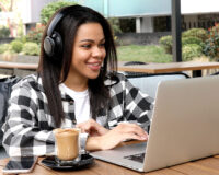 Woman wearing headphones and working on laptop while sitting at restaurant using their secure Wi-Fi