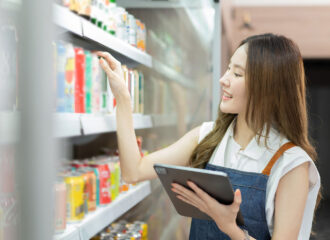 Woman at drink fridge in store looking at products