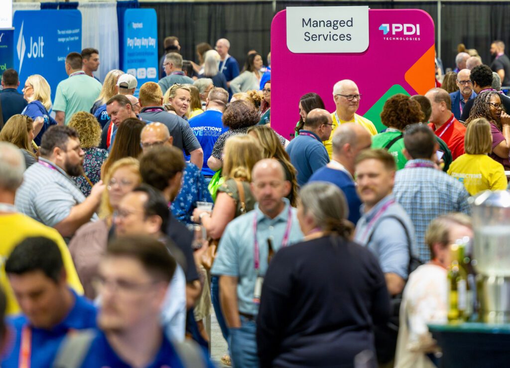 Attendees at PDI Connections Live 2024 event, engaging with various vendor booths and activities in a busy convention center.