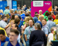 Attendees at PDI Connections Live 2024 event, engaging with various vendor booths and activities in a busy convention center.