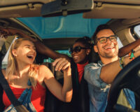 Three individuals enjoying a car ride together on a sunny day.