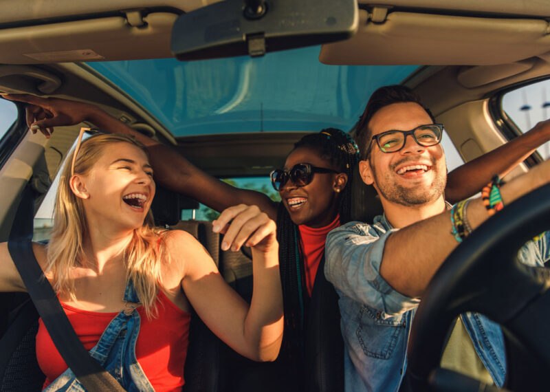 Three individuals enjoying a car ride together on a sunny day.