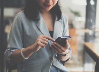 Person using smartphone to complete pay by bank enrollment in a casual setting