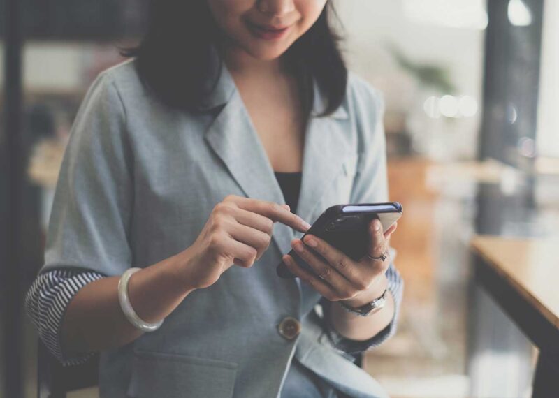 Person using smartphone to complete pay by bank enrollment in a casual setting