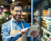 Convenience store employee using tablet technology to manage staffing and training, representing modern workforce solutions from PDI’s C-Store Workforce Guide.