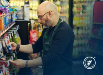 Store employee stocking shelves with packaged snacks in a convenience store, illustrating operational efficiency benefits of EDI integration from Connections Live 2025 Diamond Sponsor Fintech