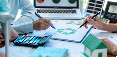 Team reviewing sustainability reports and compliance data with charts, calculator, and eco-friendly icons on a desk.